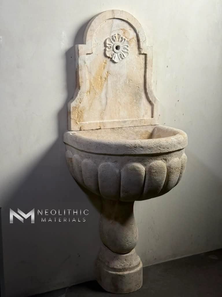 Fountain BR 136.22x21x60 captured from an elevated diagonal angle, emphasizing the deep internal volume of the stone basin and the detailed craftsmanship of the carved back panel and rosette faucet motif