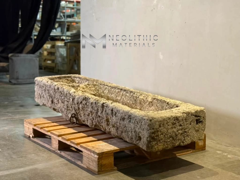 Trough FG103-57.70x19x10 long antique hand-carved stone basin with heavily weathered mossy textures resting elevated on a wooden shipping pallet inside a showroom.