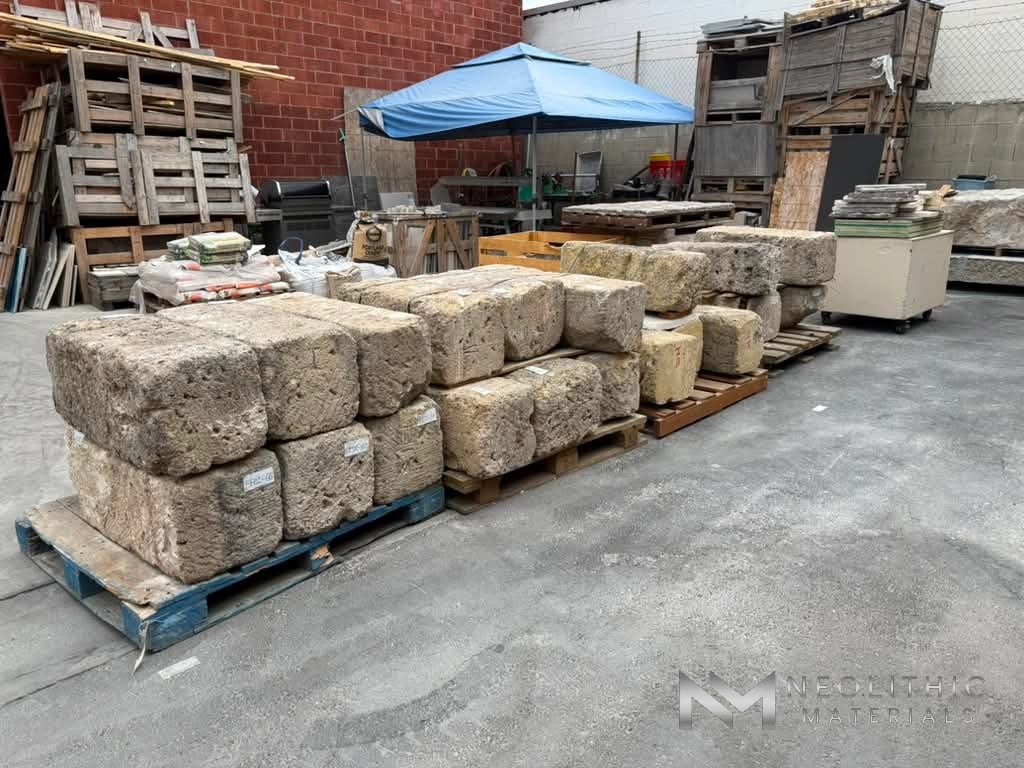 Miscellaneous FI102-50 to FI102-69 dense arrangement of vintage hand-hewn limestone blocks organized on multi-colored shipping pallets along an open concrete driveway.