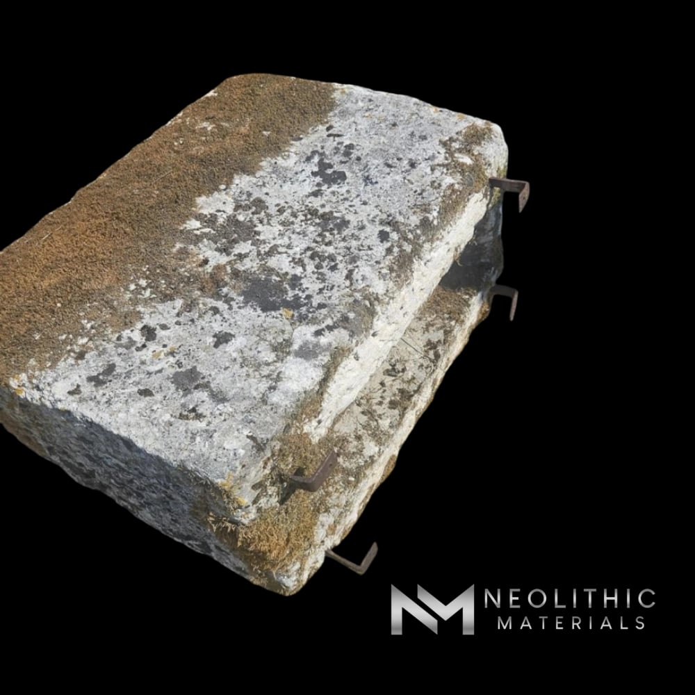 Trough FL101-02.MM side-angle outdoor perspective shot of a thick rectangular antique stone trough with a heavily distressed, lichen-encrusted grey-brown limestone surface resting on a wooden forklift pallet over a gravel lot under bright daylight.