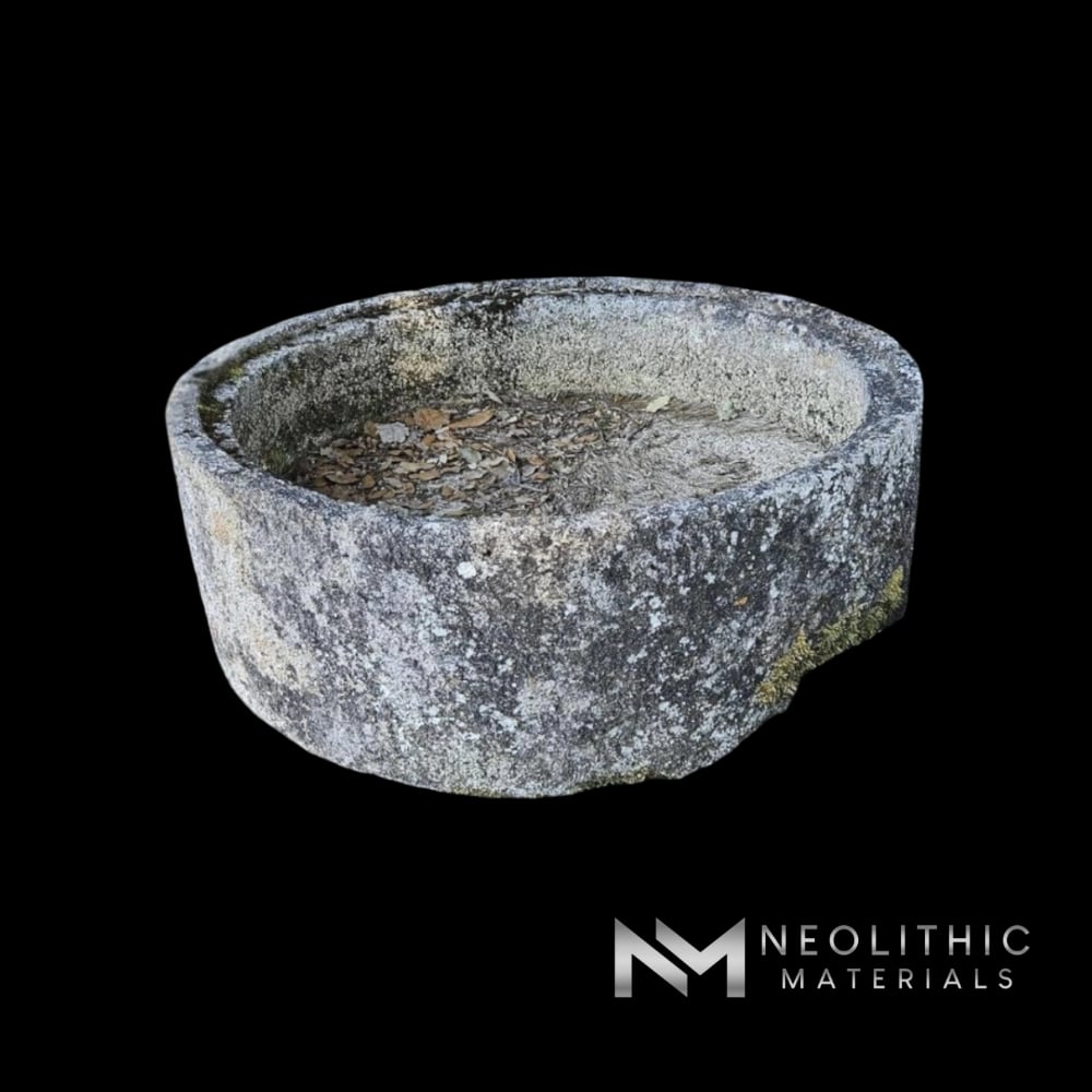 Trough FL101-06.ME weathered antique circular stone planter bowl showcased in an outdoor setting with natural side lighting.