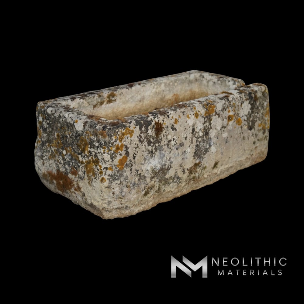 Trough FS101-06.MT close-up elevated shot of an antique rectangular stone planter basin showing its hollowed interior and heavily distressed, lichen-encrusted weathered rims sitting on a wooden pallet.