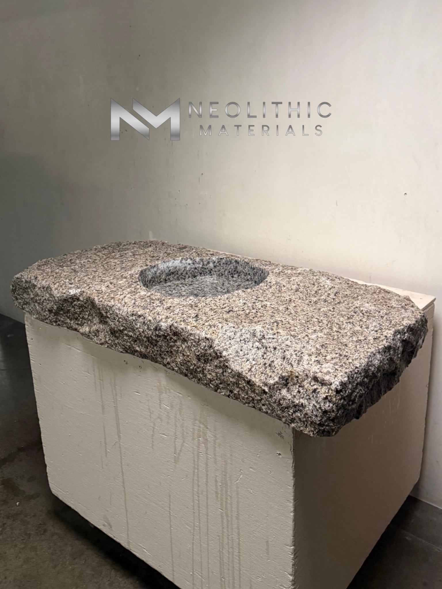 Sink UB101-11.43x19x5 medium high-angle studio perspective of a heavily speckled granite slab bathroom sink showcasing its rough chiseled split-face edges on a solid block vanity stand.